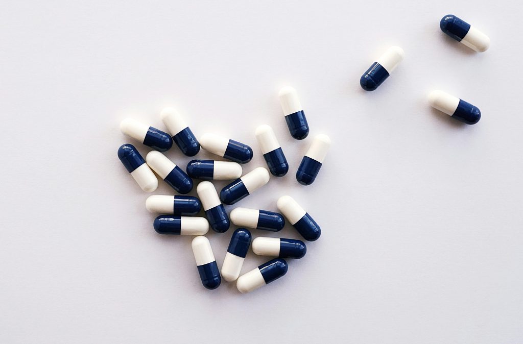 Flat lay of blue and white capsules arranged on a white surface, perfect for healthcare and medical themes.